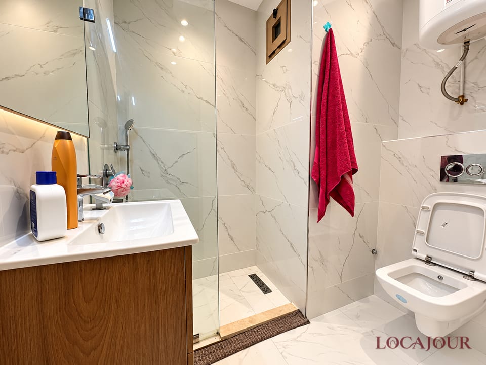 Modern bathroom in Agdal Rabat luxury furnished studio with walk in shower vanity toilet and marble style walls